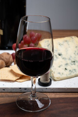 Red porto and cheese pairing, blue matured stilton English cheese served as dessert with walnuts and glass ruby porto wine