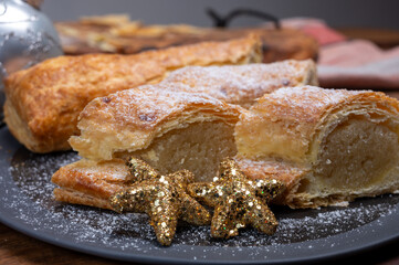 Christmas dessert, fresh baked Dutch filled spicy cookies from puff pastry with almonds on black board close up