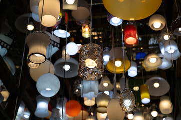 Many different ceiling lamps with lightbulbs in dark room with mirrors