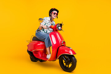 Full length photo of lovely grandma helmet travel ride red moped dressed stylish tropical print...