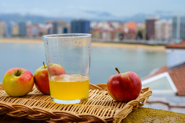 Traditional natural Asturian cider made from fermented apples in wooden barrels should be poured from great height for air bubbles into the drink and view on San Lorenzo beach of Gijon