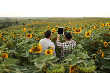 Smart farming. Back view of farmers using digital tablet for take photo, check, examine blooming...