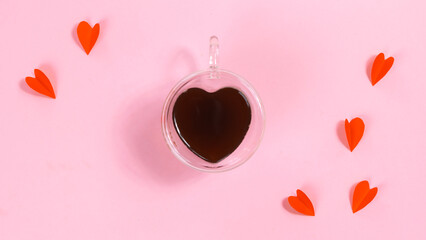 Heart-shaped cup is filled with coffee near paper butterfly hearts. The concept of love, valentine's holiday or favorite drinks.