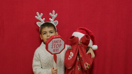Cute kids brothers hugging and showing santa stop here sign. Christmas celebration and happy...