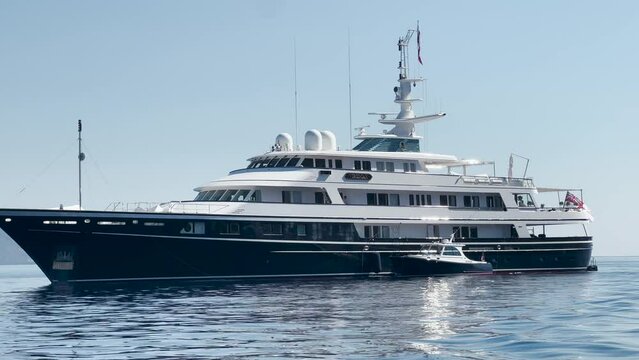 Mega yacht and a small boat in a sea near Hydra, Greece.