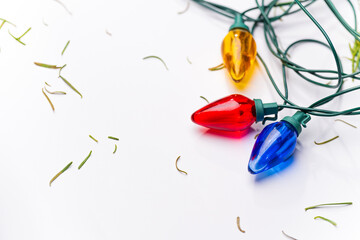 Christmas lights and stray pine needles on a white background