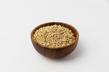 dried coriander seeds in wooden bowl, isolated in white background, concept of spice catalog, 45 degree shot