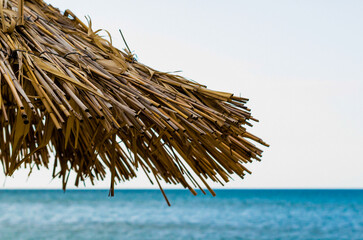 fragment of a straw beach umbrella against the background of the sea