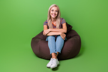 Full body photo of candid pretty girl sit brown pouf at pub folded hands over knees waiting boyfriend isolated on green color background