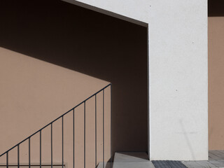 Detail of wall with shadow and stair railing in clear lines