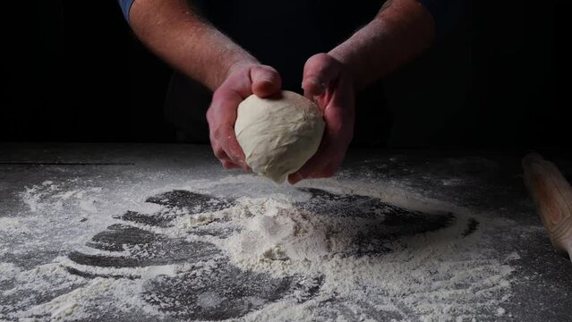 Baker throwing dough on the table with flour and flours fly. Slow motion
