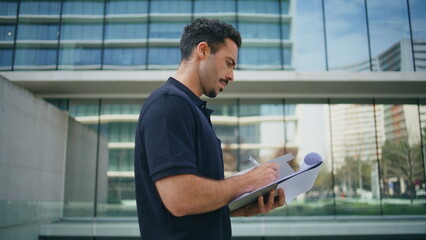 Confident businessman studying documents at street close up. Man holding papers
