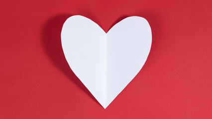 Big white heart on red background. Symbol of love. Greeting card. Concept of valentine's holiday, wedding and other occasions to express love.