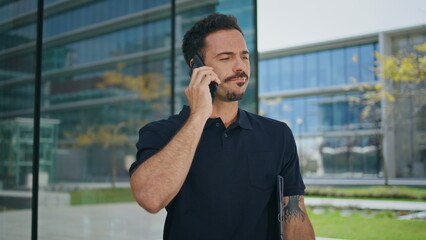 Serious guy talking phone at office building background close up. Man saying no