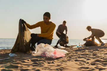 Earth day. Volunteers activists collects garbage cleaning of beach coastal zone. Woman mans with...