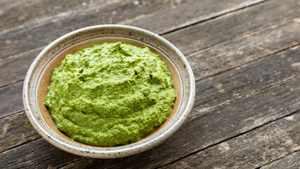 Green herbs chutney in a bowl on rustic table. - obrazy, fototapety, plakaty