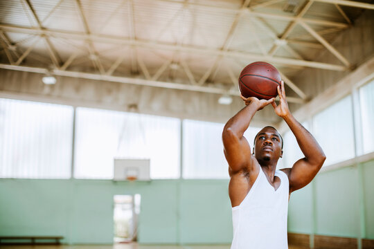 Young man shooting basketball jump shot in indoor court