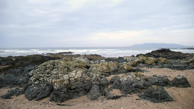 Changement de focale sur plage rocailleuse irlandaise avec vagues en fond