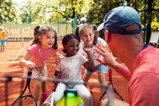 Tennis coach giving tips to little girls during practice