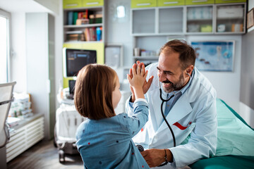 Little girl high fiving happy doctor at hospital