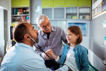 Little girl visiting doctor with grandpa at the clinic