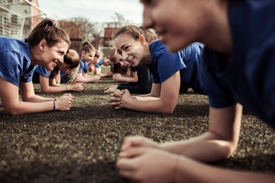 Youth female football team having practice on soccer field - Powered by Adobe