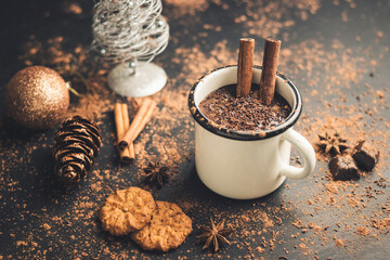 Homemade spicy hot chocolate drink with cinnamon stick, star anise, grated chocolate in enamel mug...