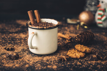 Homemade spicy hot chocolate drink with cinnamon stick, star anise, grated chocolate in enamel mug...