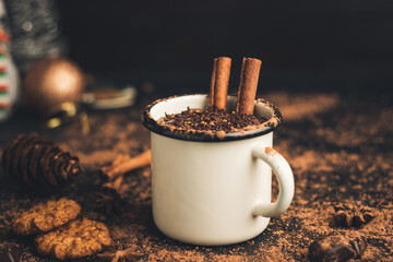 Homemade spicy hot chocolate drink with cinnamon stick, star anise, grated chocolate in enamel mug...