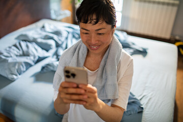 Smiling woman using smartphone after home workout