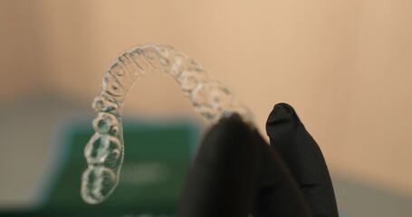 Aligners in the hands of the doctor, rubber gloves hold modern tools for teeth correction.