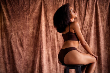 Photo portrait of pretty lovely young girl no filter sit chair show back booty dressed brown underwear isolated on studio fabric background