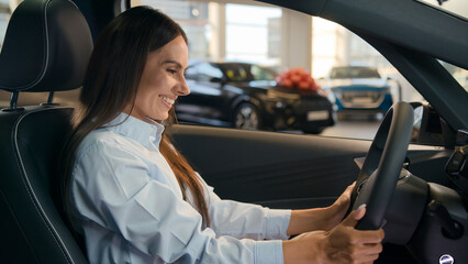 Happy Caucasian successful businesswoman joyful woman sit in new car in automobile shop rent...