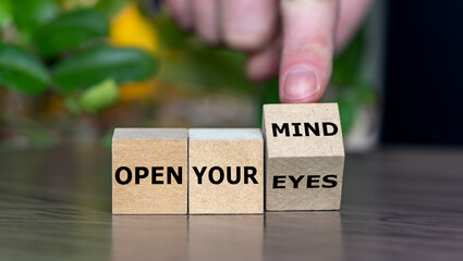 Hand turns cube and changes the expression 'open your eyes' to 'open your mind'.