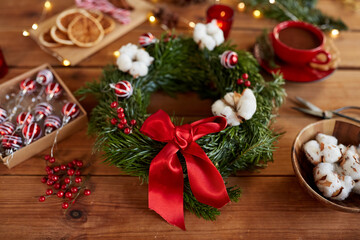 winter holidays, diy and hobby concept - close up of christmas fir wreath making stuff, decorations and hot chocolate on wooden table