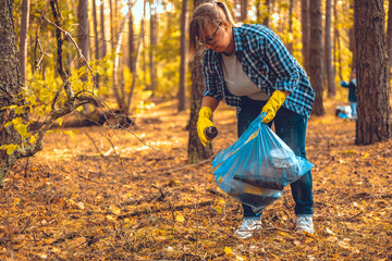Saving the forest from garbage. A female volunteer collects plastic and glass waste from the forest...