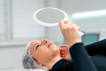 the satisfied face of a female client in a beauty salon looks in the mirror and enjoys the result...