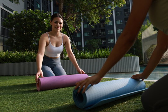 A couple young woman with sport uniform prepare yoga mats at the poolside, Yoga exercise