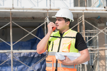 Foreman builder male at construction site. Male engineer control work by radio communication at...