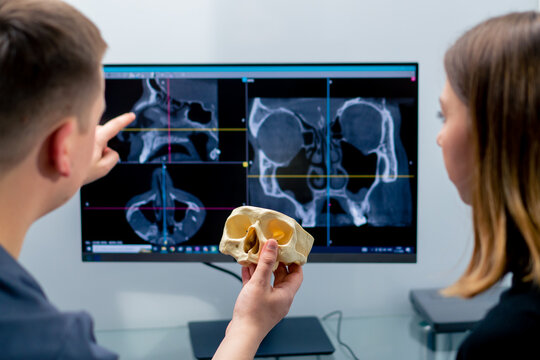 the radiologist doctor looks at the screen on which the 3D image of the nose scan shows the patient what needs to be changed during surgery