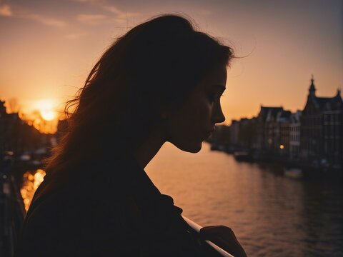 silhouette of woman watching the view from the bridge over the river in Amsterdam, sunset

