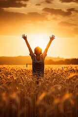 silhouette with a boy with his arms outstretched towards the sun in the sunset landscape in a wheat field
