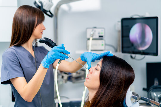 the ENT doctor performs the procedure of endoscopy of the patient's nose in the clinic holding a professional device in his hand