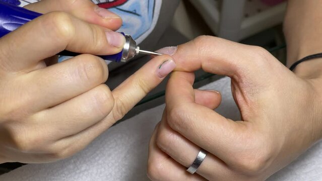 A girl doing a manicure with a special apparatus, focusing on cuticle cleansing