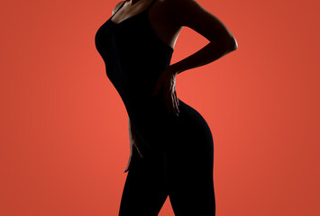 Slim sexy woman in black lingerie on a dark red background. Her skin is wet, drops of water are visible on her body. - obrazy, fototapety, plakaty