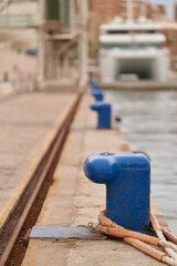 bollards with mooring ropes in the seaport with rusty rails vertical view