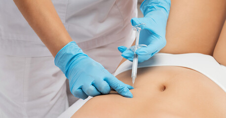 Aesthetic cosmetologist makes lipolytic injections to burn fat on the body of a woman. Female...