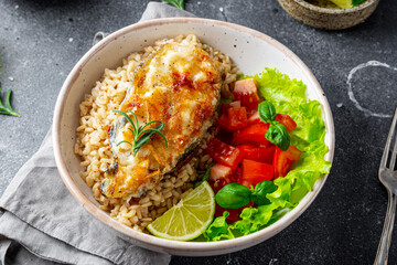 Fried catfish steak with rice and vegetable salad on a gray background