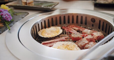 Close up juicy raw meat beef slices BBQ steak on charcoal grill with fire flame smoke, Japanese style yakiniku BBQ barbecue grill at restaurant