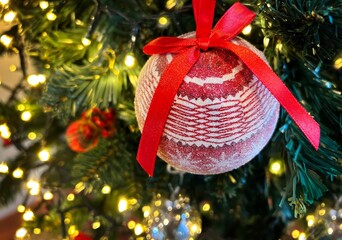 Close-up of a red ball on a Christmas tree with out of focus lights in the background, shallow depth of field. Christmas and New Year concept.